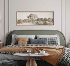 a bed with pillows and blankets on it next to a table in front of a painting