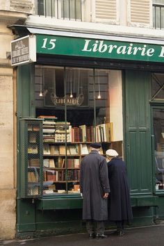 two men are standing in front of a book store looking at books on the shelves