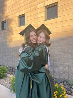 two girls in graduation gowns hugging each other