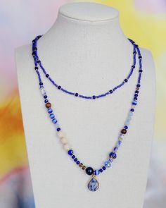 a necklace on a mannequin wearing a blue beaded necklace with a pendant