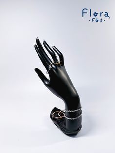 a black mannequin hand with a gold ring on it's finger and a chain around the wrist