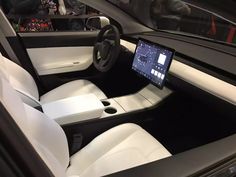 the interior of a car with white leather seats and black dash board on display at an auto show