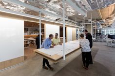 people are standing around in an office with white walls and open floor plan on the table