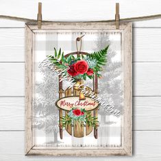 a christmas card hanging on a clothes line with a red rose and greenery in it