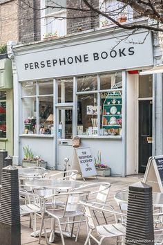 there are many tables and chairs outside of the storefront that is open for business