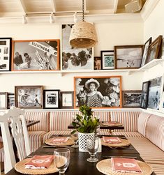 a dining room table with place settings and pictures on the wall