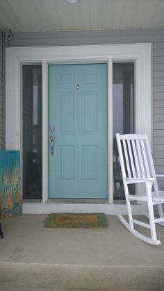 a white rocking chair sitting on top of a porch next to a blue front door