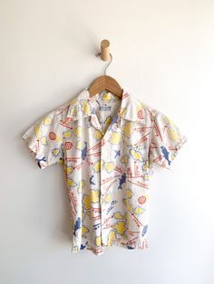 Darling cotton short sleeve Hawaiian Island motif shirt. Beautiful aging and fade. Fabric: CottonLabel: Watumull'sFit: XSEra: 1930/50’s Measurements: Bust 36" Shoulder 14" Sleeve 5.5" Sleeve hole opening (flat) 6" Length 21" Waist 34" Condition: Very good. One small hole on front and a bunch of small paint(?) dots on front (see photos). Pre-washed Short Sleeve Tops For Summer, Vintage Cotton Hawaiian Shirt For Summer, Cotton Short Sleeve Collared Shirt With All Over Print, Short Sleeve Shirt With Retro Print For Summer, Vintage Hand-printed Relaxed Fit Top, Collared Cotton Hawaiian Shirt With All-over Print, Retro Cotton Summer Shirt, Vintage Hand Printed Cotton Top, Retro Cotton Shirt For Summer