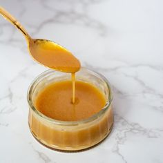 a spoon with some liquid in it on top of a glass jar filled with something