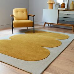 a yellow chair sitting on top of a wooden floor next to a white and gray rug