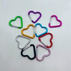 six heart shaped clips in different colors on a white surface