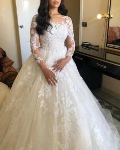 a woman in a white wedding dress standing next to a mirror with her hands on her hips