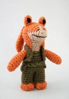 an orange crocheted stuffed animal wearing overalls