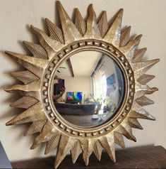 a mirror that is sitting on top of a wooden table in front of a wall