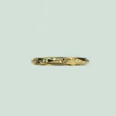 a yellow gold wedding band with an intricate design on the side and two small diamonds in the middle