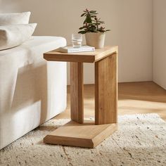 a small wooden table with a potted plant on it next to a white couch