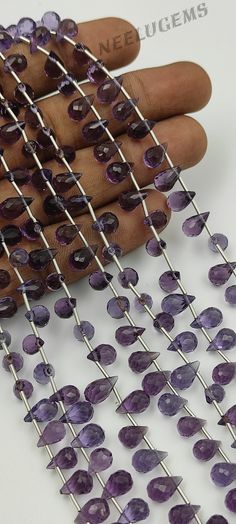 a hand is holding several pieces of purple glass beads