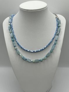 This elegant display a duo of features a serene blue  necklaces, each presenting a unique shape and size of bead, creating a symphony of sky and sea hues.  The first strand (small) features natural shell beads and the  larger cylindrical tube beads are aquamarine . The longest necklace presents a harmonious blend of spherical and tubular beads, lending a dynamic and versatile appearance. Together, they form a layered cascade of tranquil blues, perfect for adding a touch of sophistication and coo Adjustable Light Blue Necklaces With Natural Stones, Handmade Light Blue Multi-strand Jewelry, Light Blue Multi-strand Jewelry As Gift, Light Blue Multi-strand Jewelry Gift, Light Blue Multi-strand Jewelry For Gift, Turquoise Aquamarine Round Bead Necklaces, Handmade Blue Multi-strand Necklace, Elegant Light Blue Necklace With Beaded Chain, Light Blue Single Strand Jewelry For Jewelry Making