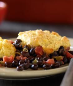 a white plate topped with black beans and an omelet next to a fork