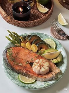 a plate with salmon, asparagus and potatoes on it next to a candle