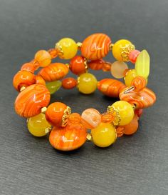 If your favorite color is yellow or orange and every color in between, this bracelet is perfect. There are beautiful oranges and yellow in this wrap bracelet and they are all stunning. The focal bead is a 16mm puffed orange circle slider. The beads around those are a swirled or marbled yellow and orange. There's also a mix of yellow and orange druzy beads. All of the metals are gold tone and include wavy spacers, pewter spikes, and two different kinds of bead caps. Fun Marble Fact: The longest marble run measures 9,379 feet. What is a druzy bead? Druzy are sets of tiny crystals of minerals formed on the surface of other stones. The overall appearance resembles that of sugar. The tiny crystals look like glitter when catching rays of light. Shipping Information All packages are shipped by Fi Orange Circle, Rays Of Light, Marble Run, Sunset Sunrise, Cat Friendly Home, Focal Bead, Bead Caps, Orange Yellow, Druzy