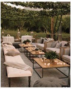 an outdoor seating area with couches, tables and candles on the tables in front of them