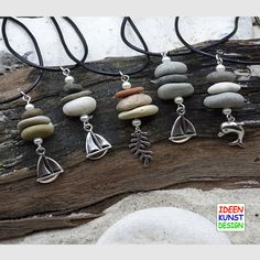 seven different necklaces with various stones and charms on them sitting on a piece of driftwood