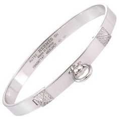 This stunning Collier de Chein collection is by Hermes, it features an authentic bangle crafted from 18k white gold with a high polished finish featuring a 6mm wide band. The front of the bangle has two small pyramid like design set with diamond and the center has a door knocker ring dangling below. It is signed by the designer with the serial number, gold content and diamond weight. Brand: Hermes Hallmark: Au750 Hermes SH Made in France 16A087147 48D0.24ct Diamond: 0.24ct (48 diamonds) Material Formal Engraved White Gold Bangle, Luxury White Gold Engraved Cuff Bracelet, Luxury Engraved White Gold Cuff Bracelet, Luxury Diamond Bangle With Polished Finish, Luxury Hallmarked White Gold Cuff Bracelet, Luxury Platinum Diamond Bracelet With Polished Finish, Designer White Gold Bracelets With Brilliant Cut, Designer White Gold Bracelet With Brilliant Cut, Designer White Gold Diamond Bangle Bracelet