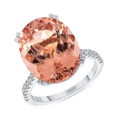 an oval cut peach quartz ring with diamonds on the shoulders and sides, set in white gold