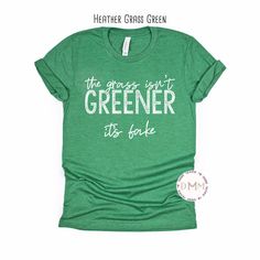 The Grass Isn't Greener It's Fake Shirt.  Graphic design in white - screen print *Heather Grass Green shirt displayed on main photo Shirt is unisex, soft and true to size. *If you like this design, but want it on a different style or brand of shirt, send a message before purchase. --------------------------------------------- PROCESSING TIME: 3-5 business days (M-F) before an item ships. If you need something sooner, please send a message before purchase. SIZING: A size chart is available in the Green Shirt With Text Print For Spring, Green Pre-shrunk Tops For Spring, Relaxed Fit Green Shirt With Text Print, Green Slogan Top For Spring, Spring Green Slogan Top, Green Cotton Shirt With Text Print, Green Cotton Slogan Shirt, Green Cotton Shirt With Slogan, Sarcastic T Shirts