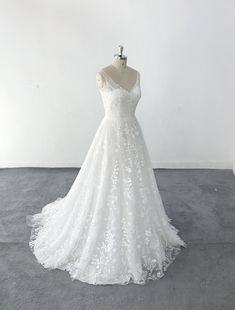 a white wedding dress on a mannequin in front of a white wall and floor