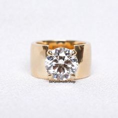 a gold ring with a round diamond on the top and bottom, sitting on a white surface