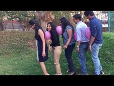 a group of young people standing around each other holding pink balloons and smiling at the camera