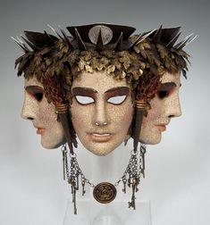 three masks with metal spikes and chains on their heads, one is wearing a necklace