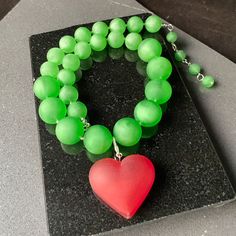 Destaca con este impresionante y único collar llamativo verde impreso en 3D. Diseñado con cuentas gruesas e inspirado en el icónico estilo Iris Apfel, este collar irradia elegancia, confianza e individualidad. El vibrante color verde añade un toque de frescura a cualquier conjunto, convirtiéndolo en un accesorio versátil y llamativo. La pieza central de este collar presenta un impresionante colgante de corazón rojo, que simboliza el amor y la pasión. Elaborado con tecnología avanzada de impresió Green Necklaces For Valentine's Day Party, Handmade Green Jewelry For Valentine's Day, Green Heart-shaped Beaded Necklace Gift, Green Heart-shaped Beaded Necklaces, Green Heart-shaped Jewelry For Party, Green Heart-shaped Party Jewelry, Green Resin Necklaces For Jewelry Making, Green Heart-shaped Beaded Necklace, Bold Resin Jewelry For Gifts