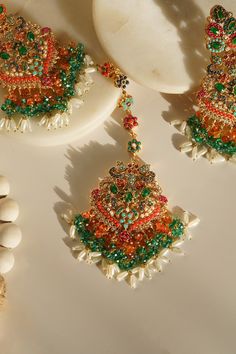 Elevate your festive attire to dreamy perfection with the Sarah - Chandelier Earrings & Maang Tikka Set, an embodiment of grandeur and allure. This exquisite earrings & maang tikka set is meticulously embellished with the splendor of multi-color stones and embellishments, adding a touch of magic to your look. The set includes a pair of stunning chandelier earrings and a maang tikka, each designed to captivate. With an approximate earring length of 3.5 inches, they are a symbol of elegance and op Festive Celebration Tikka With Tilla, Temple Jewelry Bridal Earrings For Festive Eid, Temple Jewelry Bridal Earrings For Eid, Festive Fusion Kundan Danglers, Temple Jewelry Tikka For Eid Celebration, Temple Jewelry Style Tikka For Eid Celebration, Fusion Style Kundan Danglers For Festive Occasions, Eid Celebration Temple Jewelry Tikka, Hand Set Tikka For Festivals And Celebrations