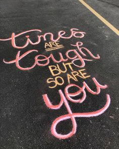 chalk writing that says times are rough but so are you on the pavement in an empty parking lot