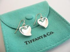 Overview:Time to pull your hair back and show off your awesome earrings!  Offered for sale is a gorgeous and elegant pair of Tiffany and Co. Sterling Silver Peretti Carved Heart Dangling earrings.   This pair looks fabulous, cosmopolitan, and yet retains a very dainty and feminine touch to it.  Extremely elegant and comfortable piece! You will feel playful, modern and super stylish while wearing these earrings.  Great pair to wear for work, a night in town, at a party, or just going to dinner Elegant Single Heart Earring For Valentine's Day, Elegant Single Heart Cut Earring, Elegant Pierced Heart Earrings For Valentine's Day, Luxury Heart Cut Sterling Silver Earrings, Luxury Earrings With Heart Charm, Elegant Heart-shaped Earrings For Gifts, Luxury Heart Charm Earrings For Valentine's Day, Luxury Valentine's Day Earrings For Pierced Ears, Luxury Heart-shaped Drop Earrings For Valentine's Day