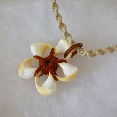 a white flower is attached to a brown string on a white tablecloth with rope