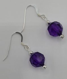 The earrings are made with a single round purple crystal bead and silver seed beads.  Earrings hang a total of 1 1/2 inches in length and have a sterling silver earring wire. Sterling Silver Faceted Beads Earrings For Gift, Beaded Sterling Silver Crystal Earrings, Sterling Silver Beaded Crystal Earrings, Purple Drop Crystal Earrings Nickel Free, Sterling Silver Earrings With Faceted Beads For Gifts, Nickel-free Purple Beaded Round Earrings, Nickel Free Sterling Silver Beaded Earrings, Nickel Free Purple Crystal Drop Earrings, Nickel-free Round Sterling Silver Beaded Earrings