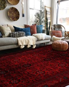 a living room filled with lots of furniture and pillows on top of a red rug