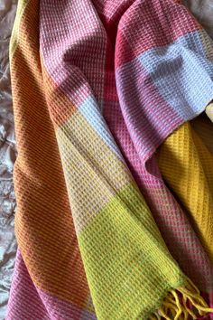 a multicolored scarf laying on top of a bed