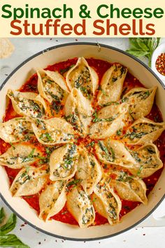 spinach and cheese stuffed shells in a skillet on a white table with herbs