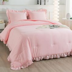 a pink comforter with ruffled edges on a bed