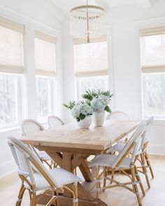 a dining room table with white chairs and flowers