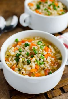 two white bowls filled with soup on top of a wooden table