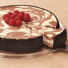 a chocolate cheesecake with raspberries on top is sitting on a glass plate