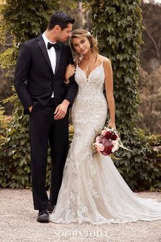 a bride and groom pose for a photo in front of an ivy - covered archway