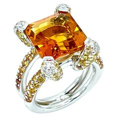 A truly stunning work of art! This Madeira Citrine fires up with light. It is emerald cut and weighs 6.00 carats, set with four Diamond and Citrine pave prongs, with a pave Citrine split shank in 18K white gold. There are 0.26 carats in round brilliant Diamonds, with an additional 2.00 carats in round cut Citrines. The shank is stamped "750". The ring is currently a size 6.25, and can be adjusted. Offered by Charles Schwartz & Son Jewelers. Luxury Multi-stone Yellow Gemstones, Luxury Yellow Multi-stone Gemstones, Orange Brilliant Cut Jewelry For Gift, Luxury Citrine Topaz Ring With Emerald Cut, Luxury Cushion Cut Citrine Jewelry, Luxury Topaz Jewelry With Polished Finish, Luxury Polished Topaz Jewelry, Luxury Citrine Cushion Cut Jewelry, Luxury Yellow Sapphire Ring