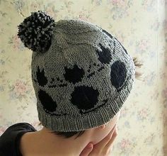 a young child wearing a knitted hat with black and white skulls on the front